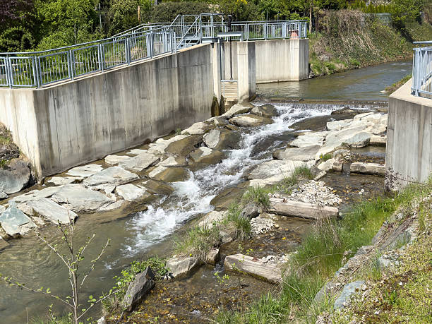 istock Modern river dam structure with flowing water and concrete barriers in nature 2212370543