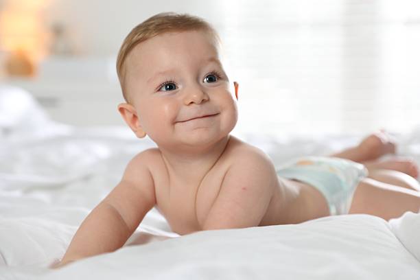 istock Cute little baby in diaper on bed at home 2212371922