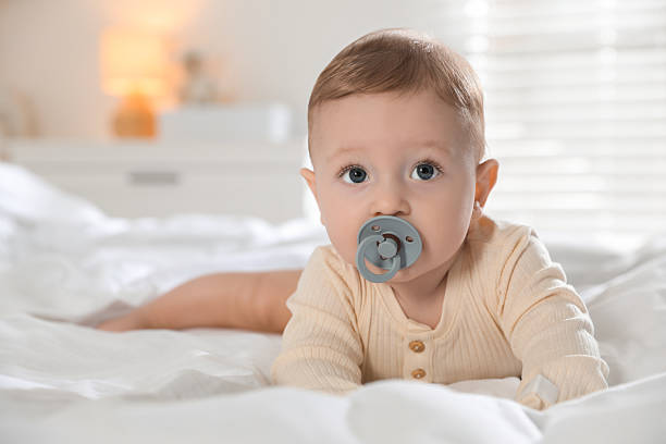 istock Cute little baby with pacifier on bed indoors 2212371957