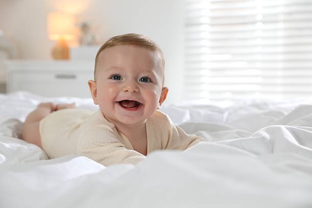 istock Cute little baby on bed at home, space for text 2212371984
