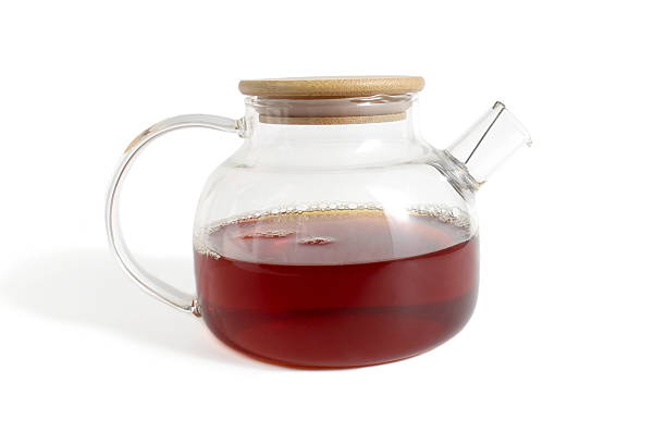 There is a glass teapot with tea on a white background.