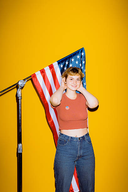 istock Confident young adult with American flag by yellow wall 2212374541