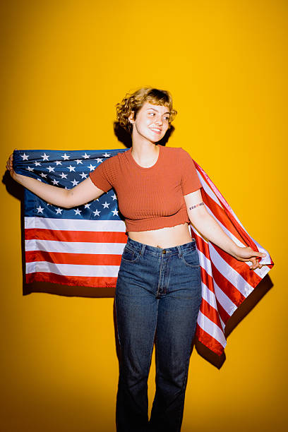 istock Joyful celebration with an American flag and a bright yellow backdrop 2212374633