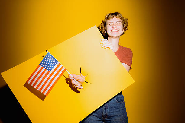 istock Young woman joyfully celebrates with flag and colorful backdrop 2212374740