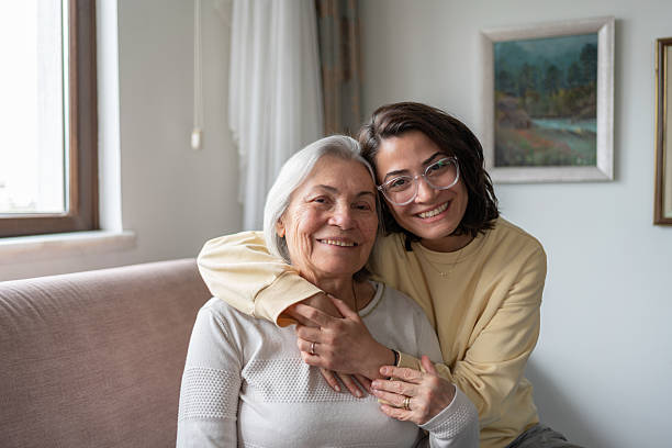 istock Daughter Hugging Senior Mother From Behind Holding Hands 2212374780