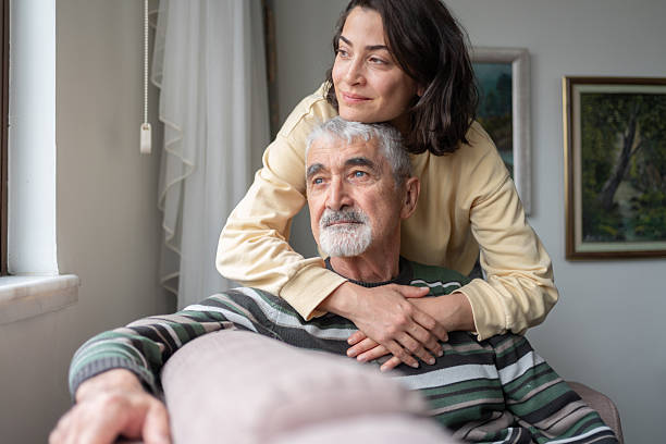 Daughter Hugging Senior Father From Behind Holding Hands
