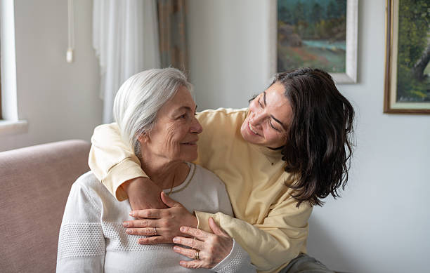 istock Daughter Hugging Senior Mother From Behind Holding Hands 2212374820