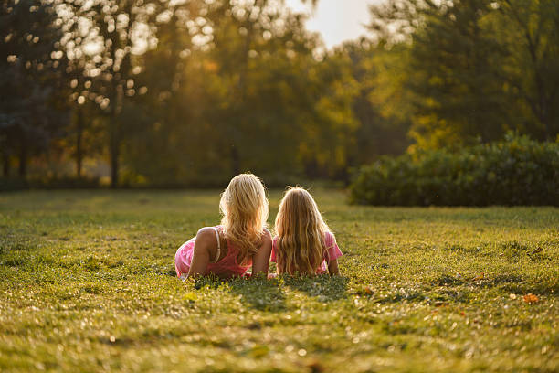 istock Woman and her daughter enjoying lying on the grass in publlic park 2212374821
