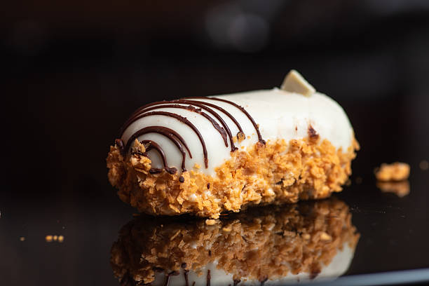 These delectable white chocolate pastries are artistically arranged on a stone slab. Topped with nuts and drizzled with chocolate, they promise a taste sensation and visual delight.