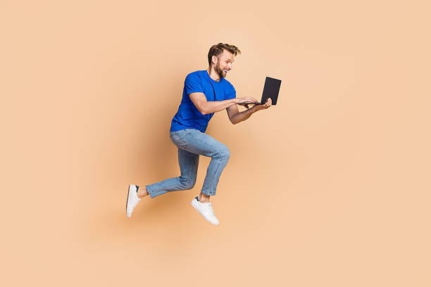 istock Full size profile side photo of young energetic guy type chat laptop jump up agent isolated over beige color background 2212376545