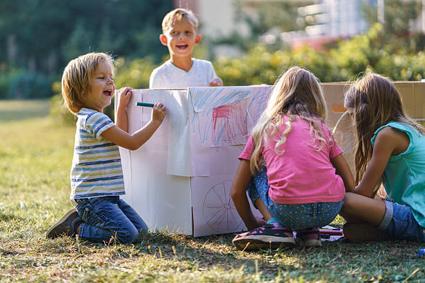 istock Children having fun drawing on carboard box in public park 2212377280