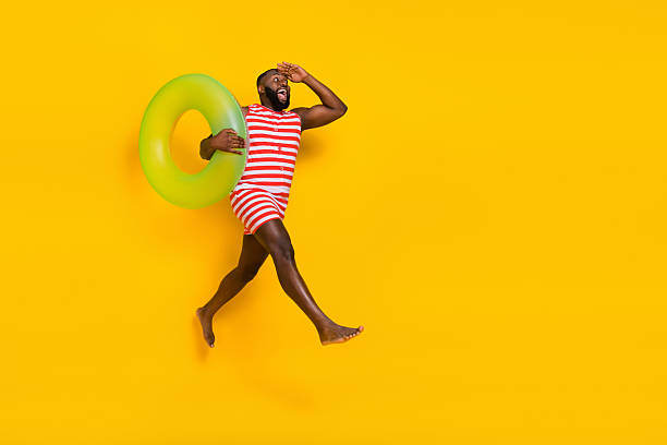 Barefoot guy jump see empty space go fast hold rubber circle wear swim suit red shorts isolated bright color background.