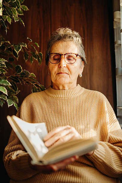 istock Senior caucasian woman reading book by the window 2212379415