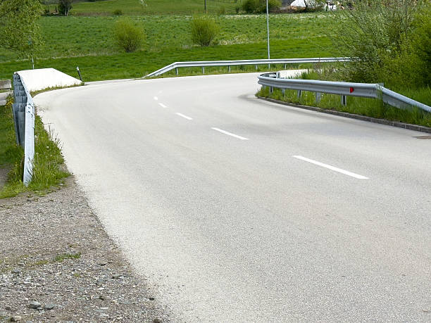 istock Empty country road with green fields and guardrails in serene landscape 2212380677