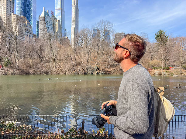 istock Man Enjoying Scenic City Park View with Camera 2212384239