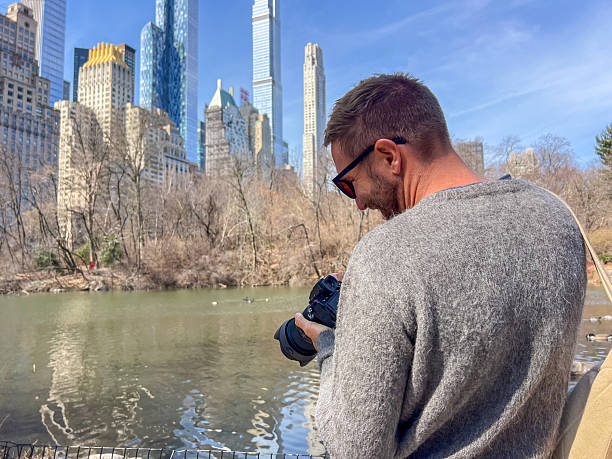 istock Man Enjoying Scenic City Park View with Camera 2212384264
