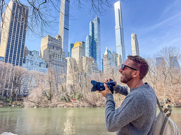 istock Photographer Capturing Cityscape in Urban Park Setting 2212384574