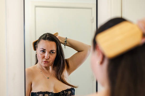 A woman gently combs her hair as part of her daily beauty care routine, promoting healthy, smooth, and well-groomed locks.