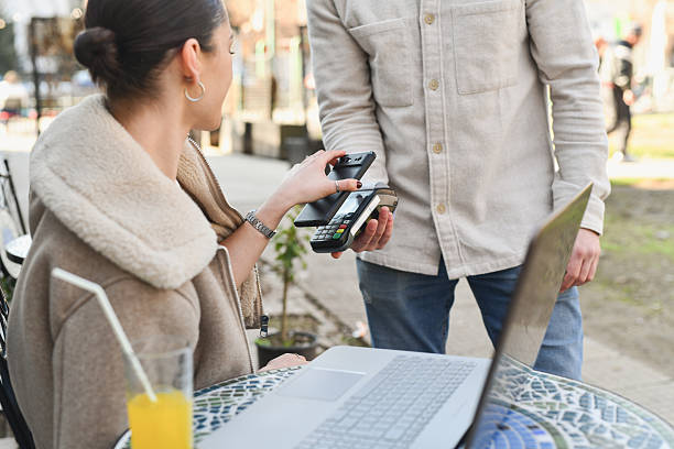 istock Waiter Processing Mobile Payment as Woman is Using Her Smartphone Paying for Drink 2212390442