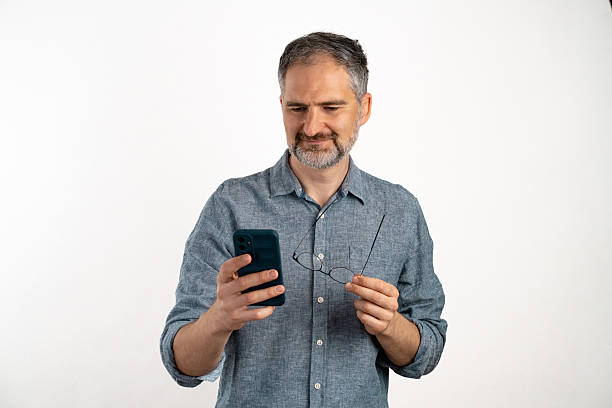 istock Man smiling while holding a phone standing against a white background 2212391259