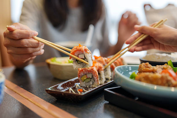 istock Sharing Sushi Rolls with Chopsticks at Japanese Restaurant 2212395518