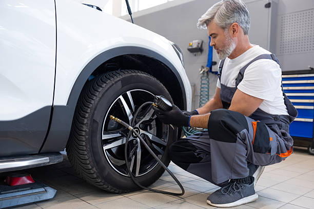 istock Mechanic inflating tire with pressure gauge in workshop 2212398437