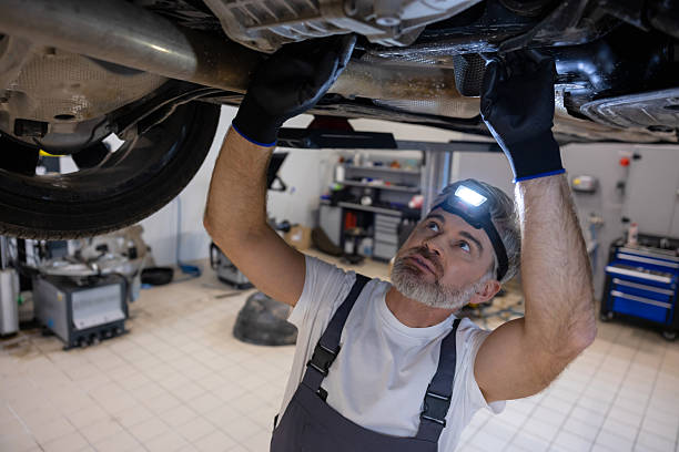 istock Mechanic inspecting undercarriage with headlamp 2212398523
