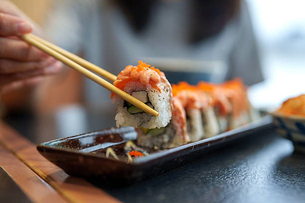Fresh Salmon Sushi Roll Being Picked with Chopsticks
