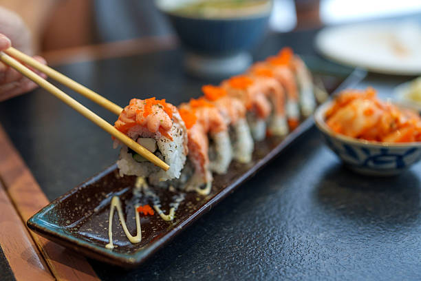 istock Fresh Salmon Sushi Roll Being Picked with Chopsticks 2212399652