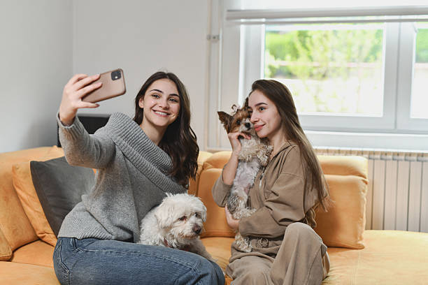 istock Women Cuddling Their Cute Dogs While Taking Fun Selfie Together 2212400813