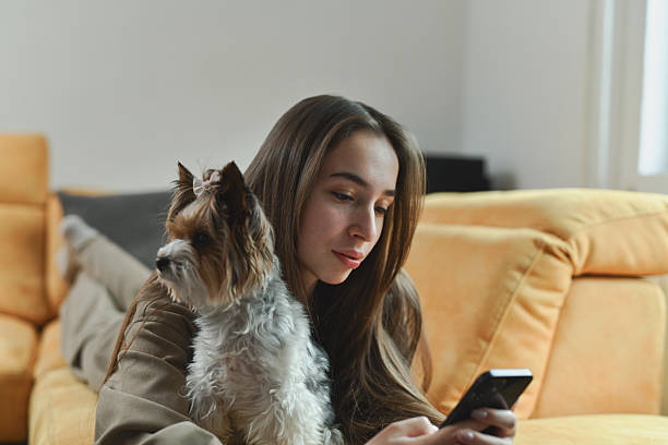 istock Female Scrolling Through Social Media While Embracing Her Dog and Lying on Sofa 2212401107