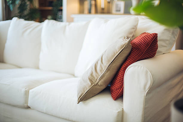 istock Comfortable white sofa with cushions in a bright living room 2212401849