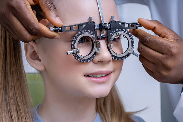 istock Doctor adjusting optometric tool while testing vision of a girl 2212404927