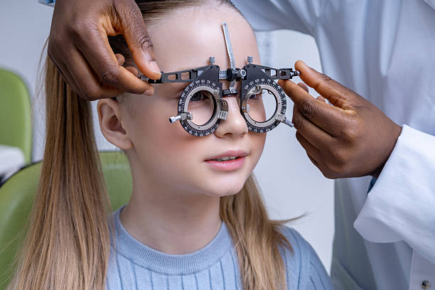 istock Doctor adjusting optometric tool while testing vision of a girl 2212404938