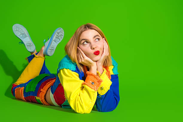 istock Colorful young woman in patchwork outfit lying on green background emphasizing self-expression 2212405448