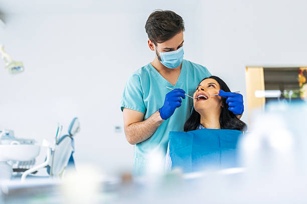 istock Smiling Dentist Treating Patient in Bright Dental Office 2212412570