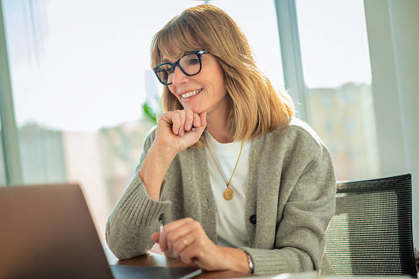 istock Blond haired businesswoman sitting in a modern office and using her laptop 2212414329