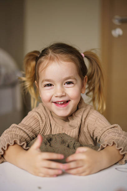 istock Happy girl playing whit sand at the table 2212414973