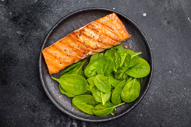 istock Roast salmon fillet steak with spinach. black background. top view 2212417306