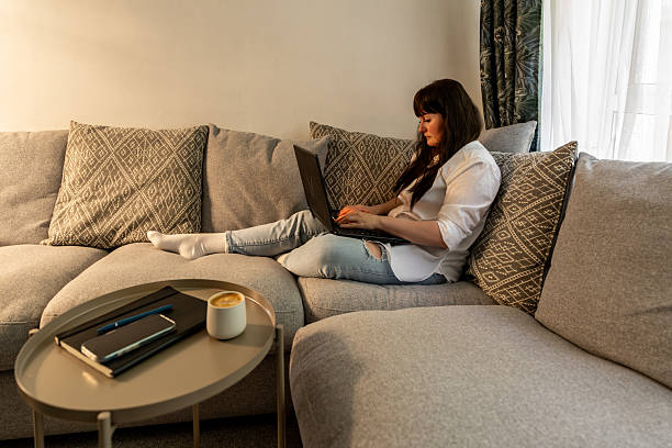 istock Woman working from home sitting on comfortable sofa using laptop 2212417491