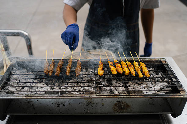 Satay cooking on a flaming barbecue grill. Festival celebration.