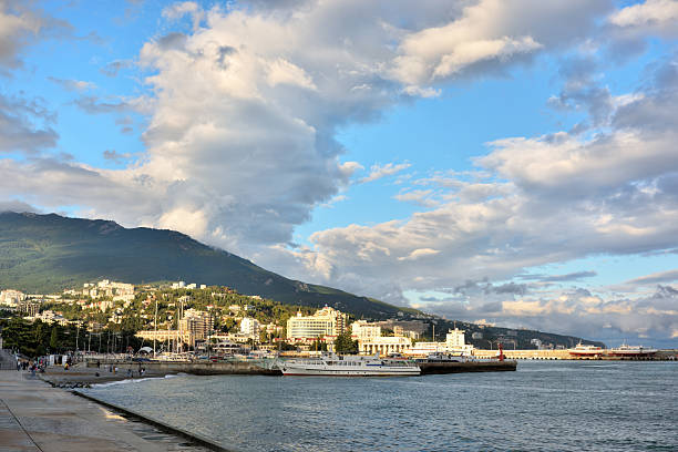 Beautiful cumulus clouds over the mountains in Yalta. The port of Yalta illuminated by the morning rays of the sun.
