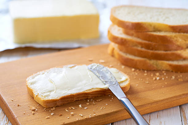 istock Tasty cut wheat bread  with fresh butter on a white wooden table. 2212422406
