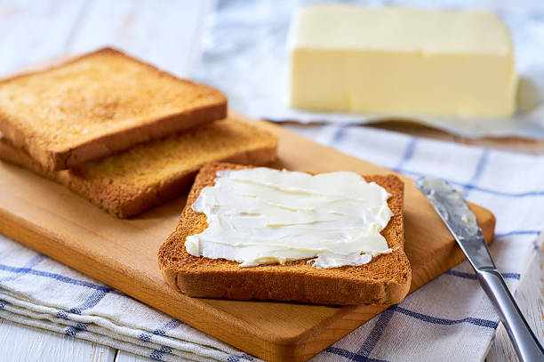 istock buttering slices of toast bread on a light wooden table, selective focus. 2212422475