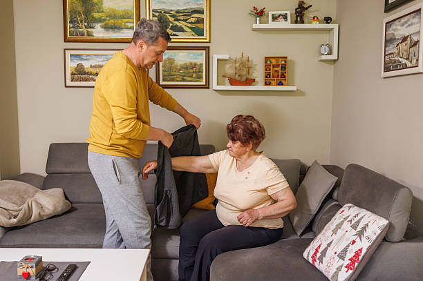istock Elderly Woman Receiving Help Dressing from Devoted Son 2212426262