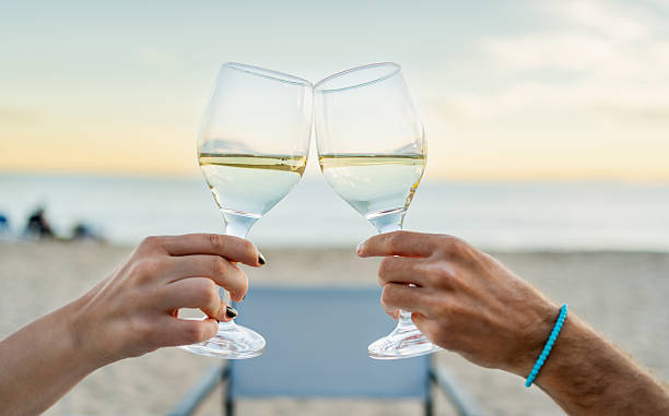 istock Couple toasting with white wine on beach at sunset 2212426562