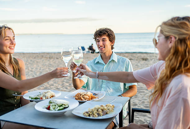 istock Friends toasting with wine at beach restaurant: enjoying a seaside dinner 2212427316