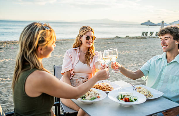 istock Friends toasting white wine at beach restaurant enjoying seaside dinner 2212427704