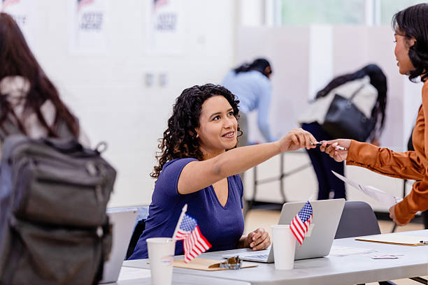 istock Young Woman Receiving Pen at Voting Booth 2212431586