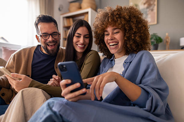 istock Three Diverse Friends Laughing Together While Sharing Social Media Content On Smartphones At Home 2212432770